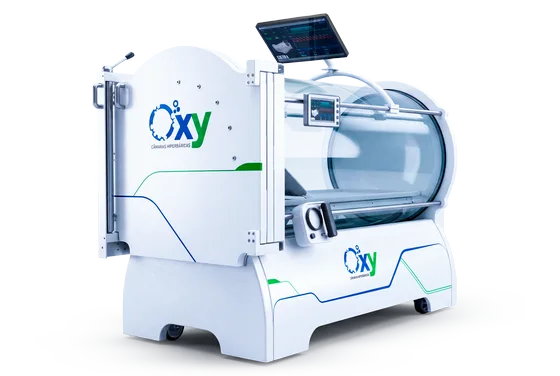 Câmara hiperbárica monoplace Oxy da linha atual em três quartos, com carenagem branca fechada, cúpula de acrílico transparente por todo o vaso, tela de comando no trilho e monitor no braço articulado